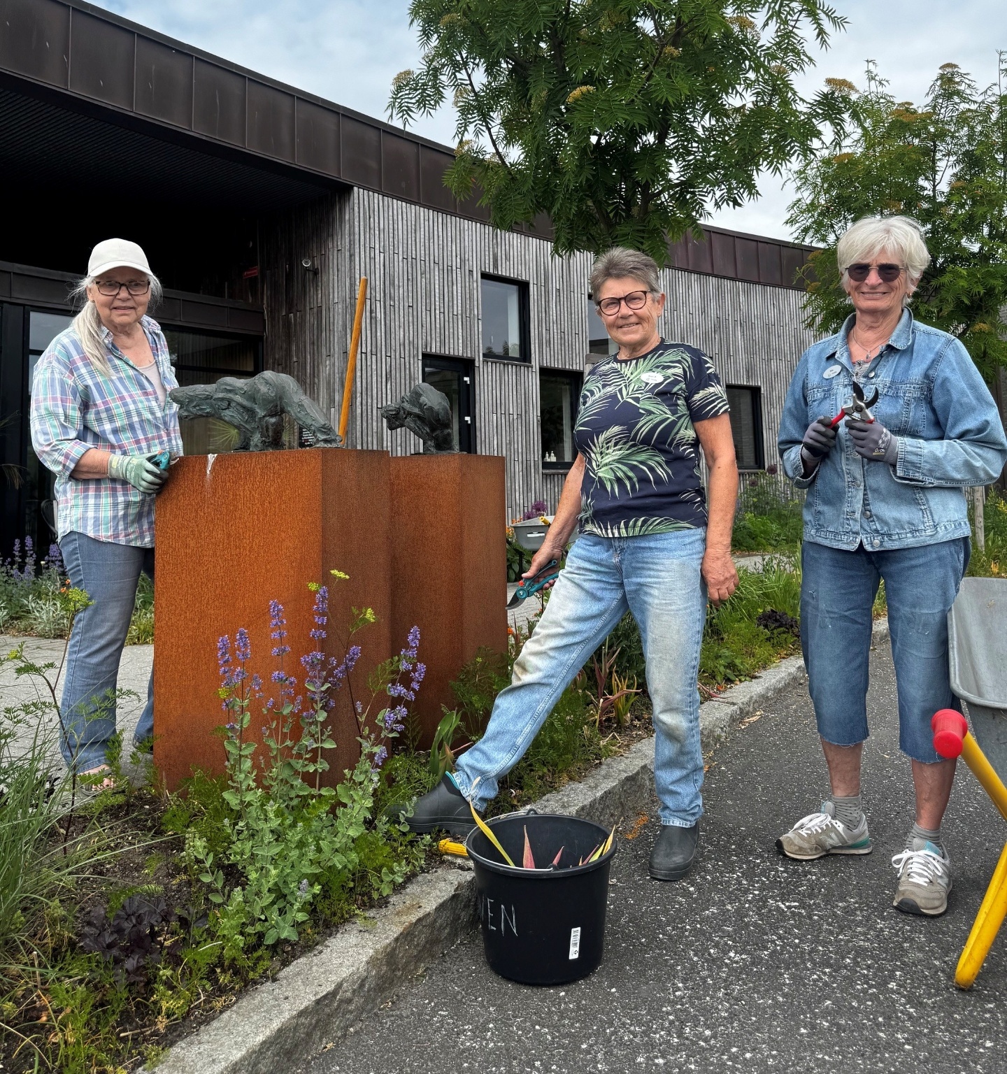 Tre frivillige fra Greenteam ved havetroldene foran Hospice Djursland