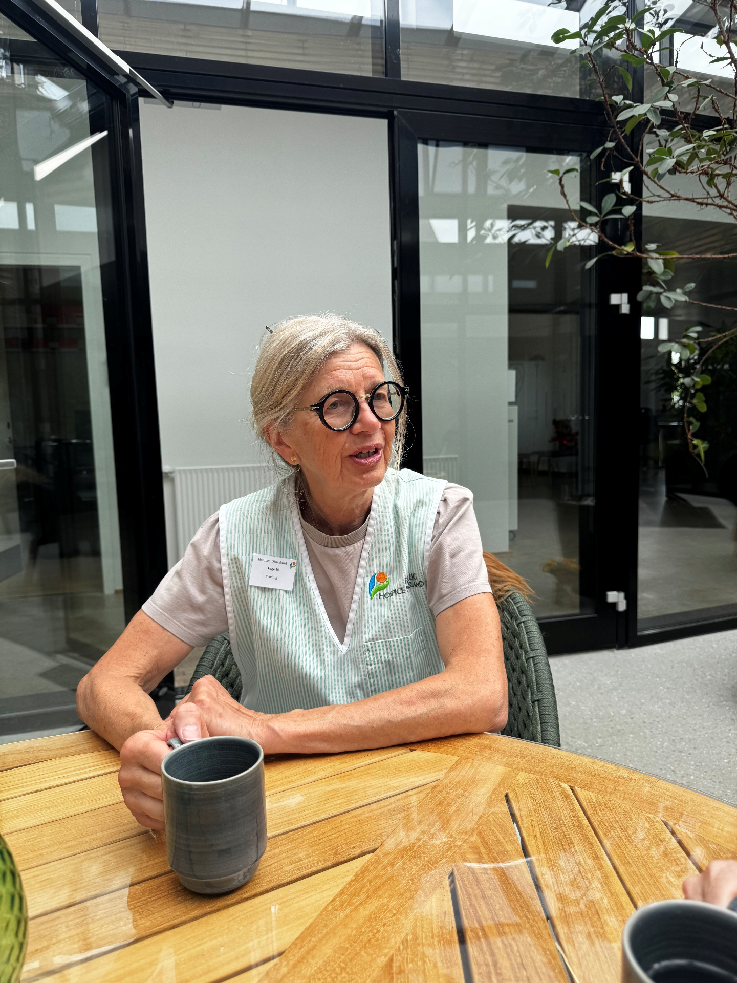 Frivillig madanretter Inge ved bordet i atriumgården