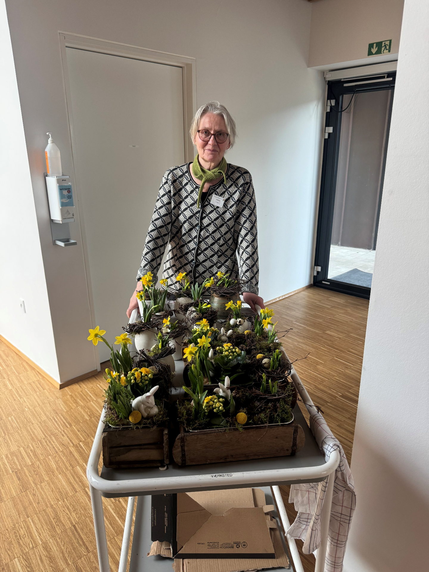 Frivillig blomsterpige med påskedekorationer på rullebord
